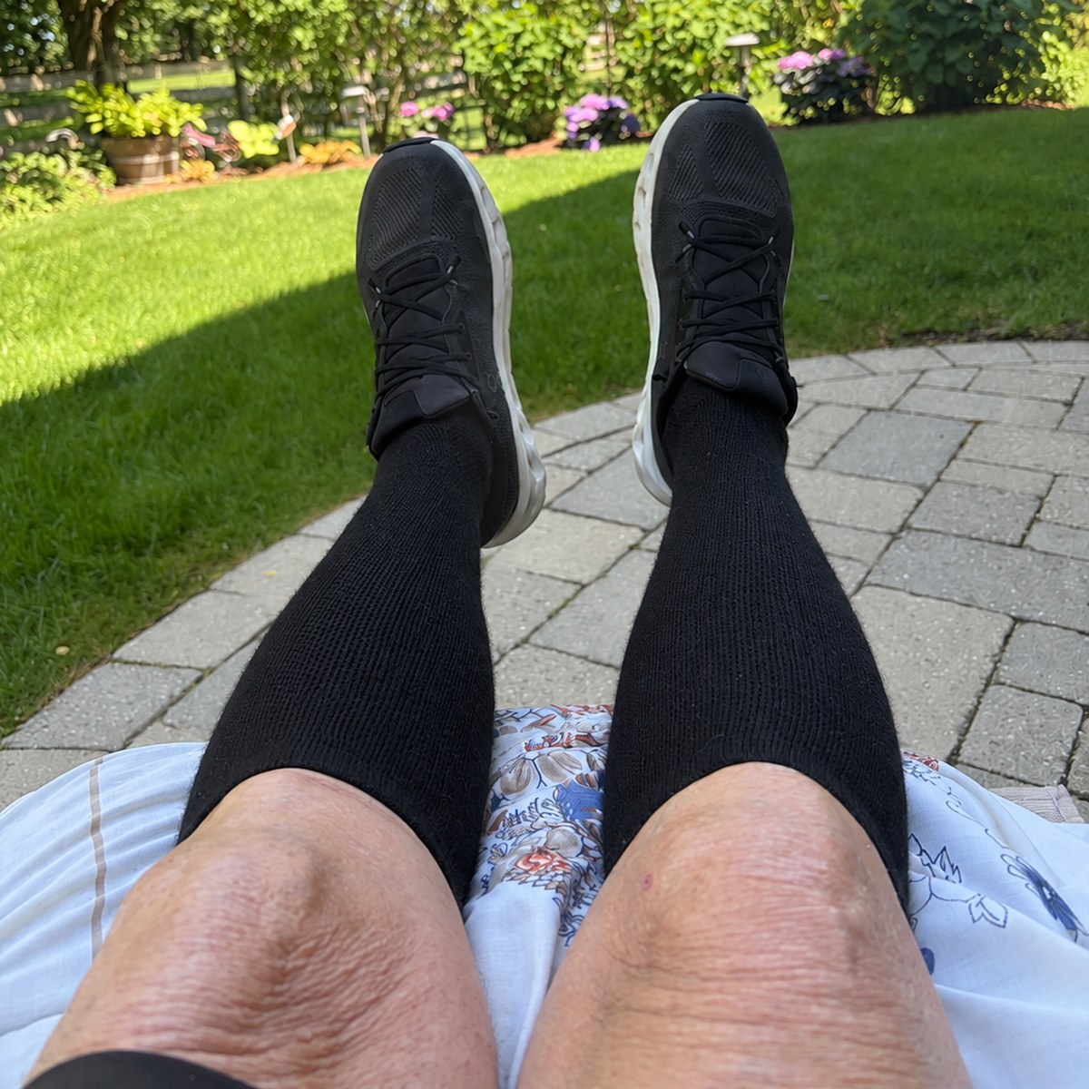 Customer photo from Douglas G. — black knee high compression socks worn with trainers, feet up in a garden