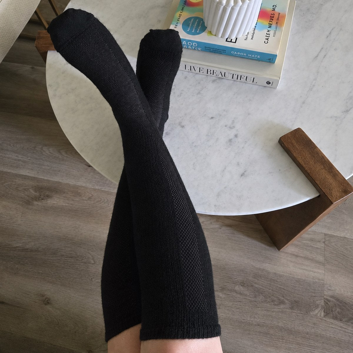Customer photo from Valeria S. — black knee high compression socks, legs resting on a marble table